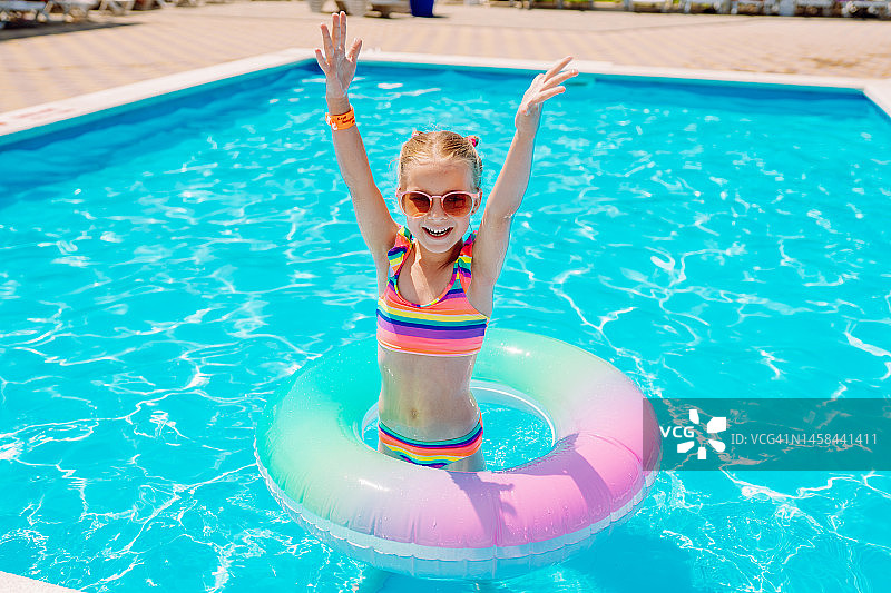 儿童充气救生圈：泳池中拿着彩色游泳圈的女孩图片素材