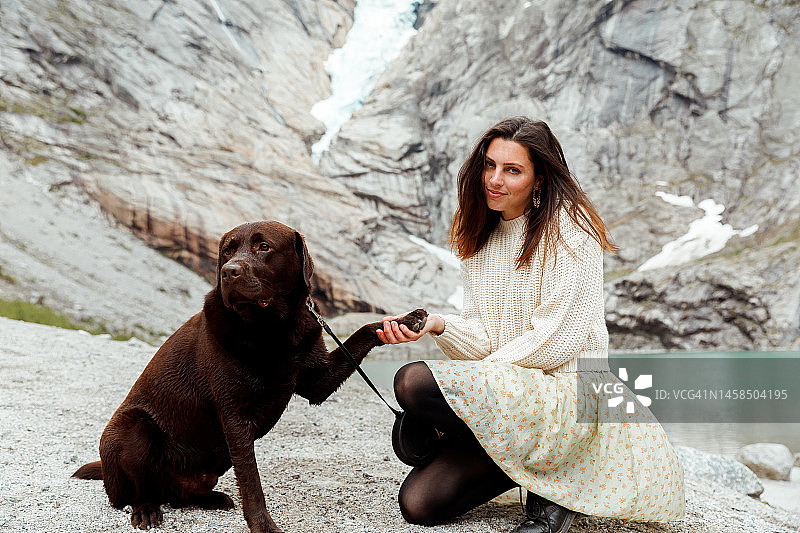 年轻女人在冰川上和她的狗玩耍图片素材