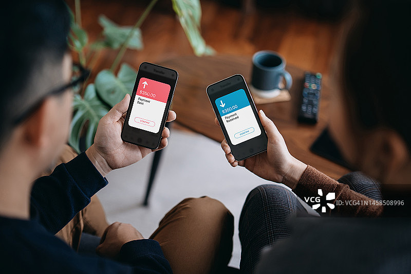 年轻夫妇用手机通过数字钱包收发款，使用网上银行APP。朋友用手机激活NFC，非接触式支付，智能银行科技图片素材