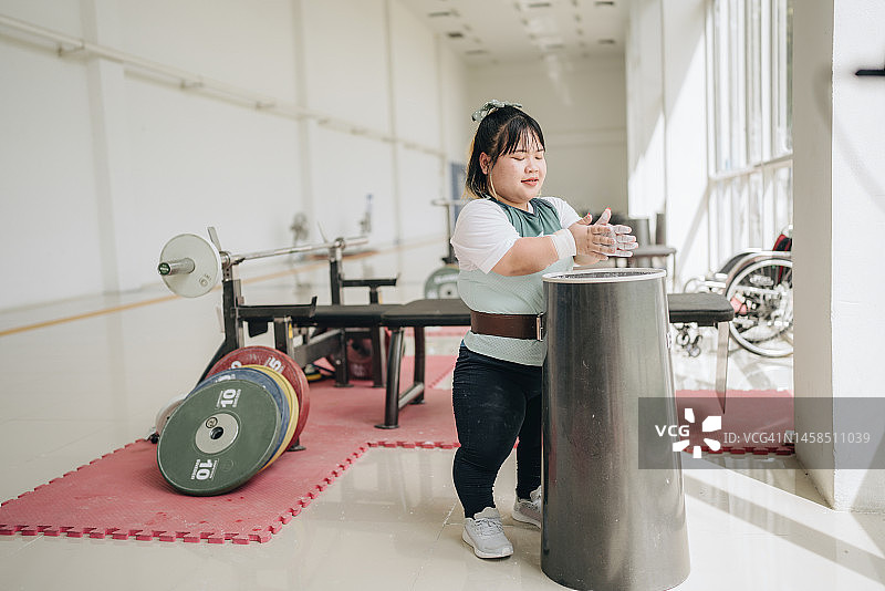 坐轮椅的亚裔女运动员在健身房锻炼前做准备图片素材
