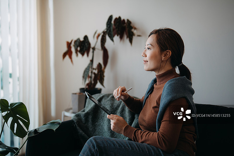 年轻的亚洲女人在家使用平板电脑，查看银行账户图片素材