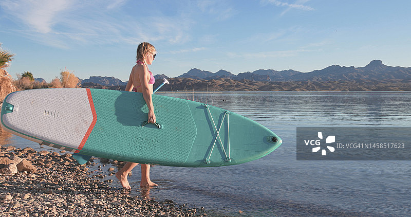 女子桨板冲浪者前往湖岸图片素材