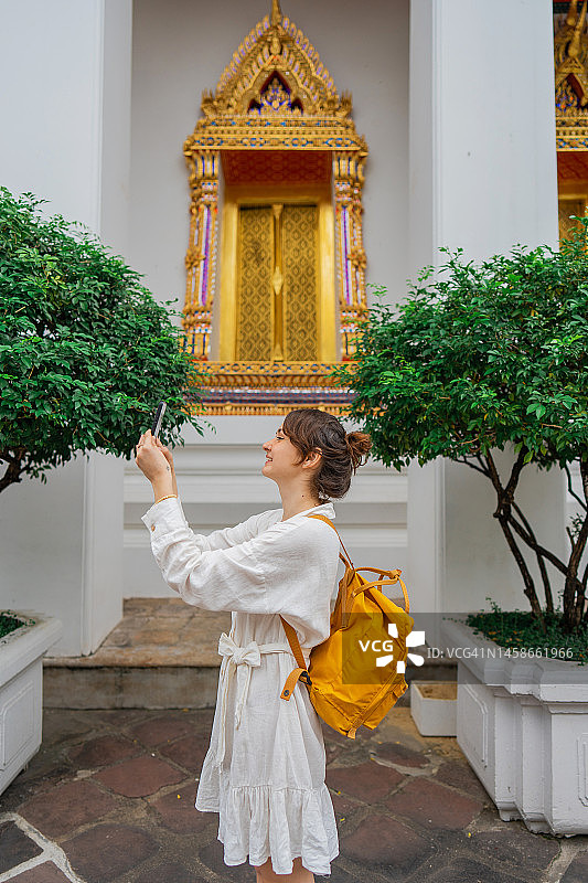 在曼谷卧佛寺用智能手机拍照的女人图片素材