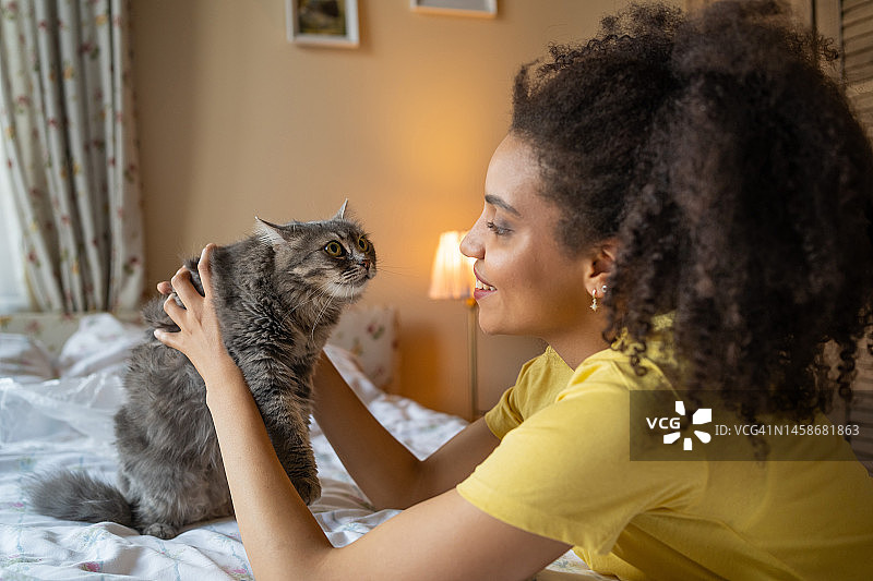 在家抚摸宠物的年轻非洲裔妇女图片素材
