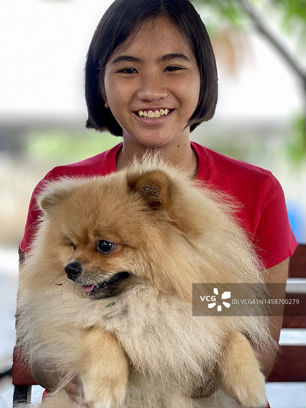 抱着博美犬的亚洲少女图片素材