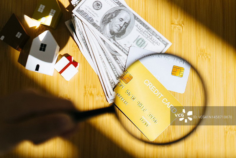 选择性聚焦信用卡、小礼品和房屋上的放大镜，房屋贷款和房地产概念图片素材
