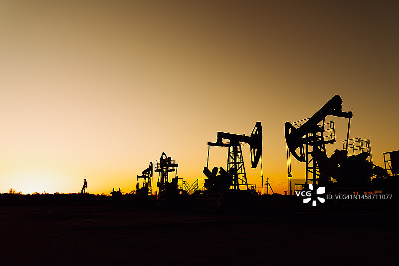 油田抽油机剪影。资源开采。环境问题、污染和损害、生态风险图片素材