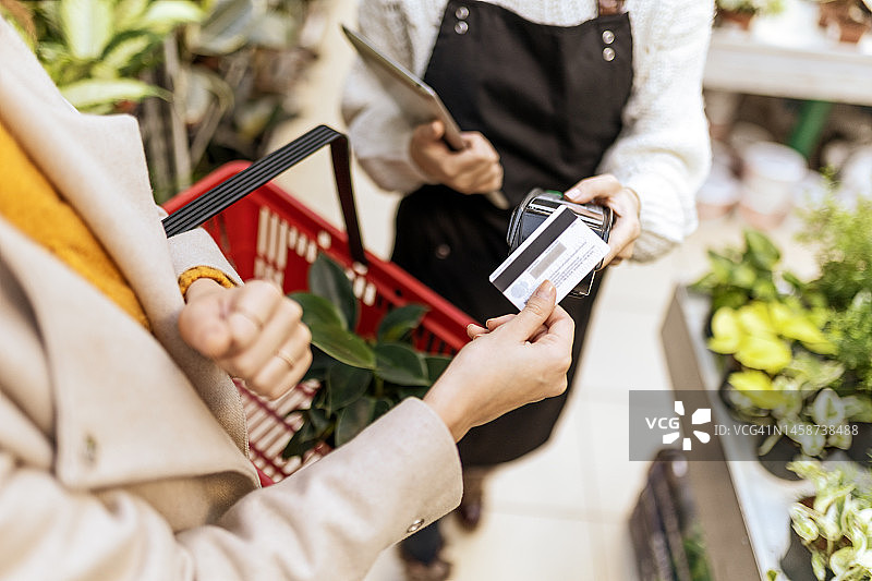 女子在园艺中心用信用卡购买盆栽植物图片素材