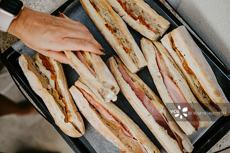 抓取夹着火腿和奶酪的三明治的手图片素材