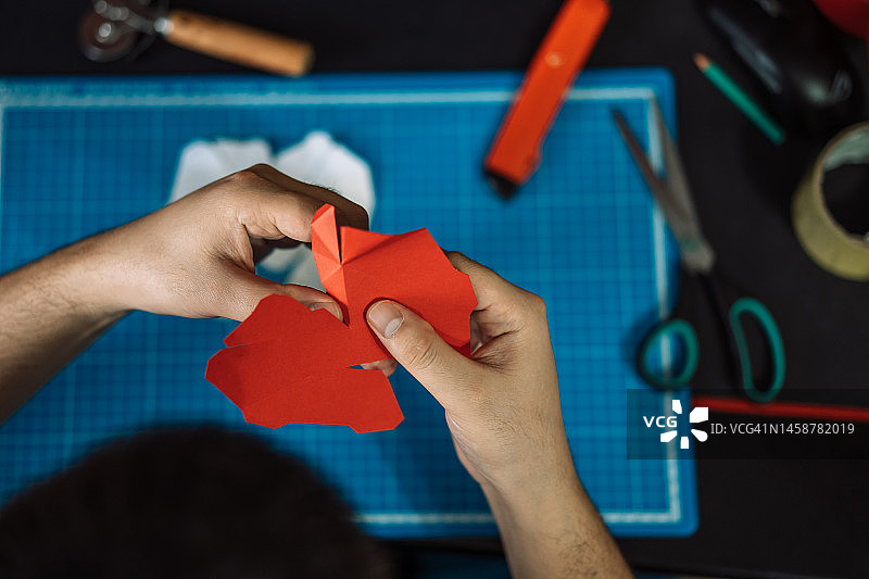 戴着耳机男子用自己的双手从红色纸上收集一颗心图片素材