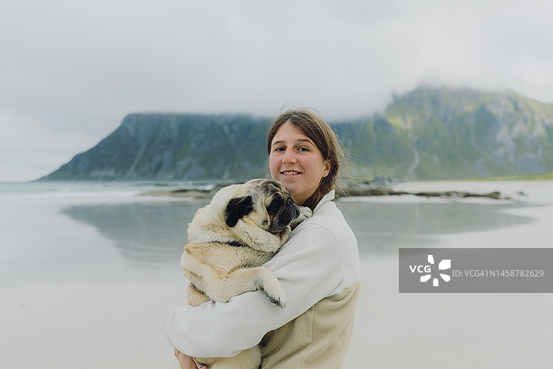 快乐的女人在罗弗敦群岛海滩上与她的狗散步图片素材