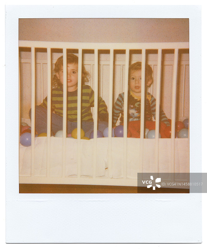 兄妹在婴儿床里玩假装的球池图片素材