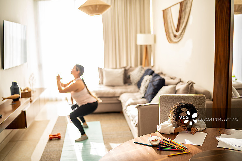 幼儿女孩在妈妈锻炼时画画图片素材