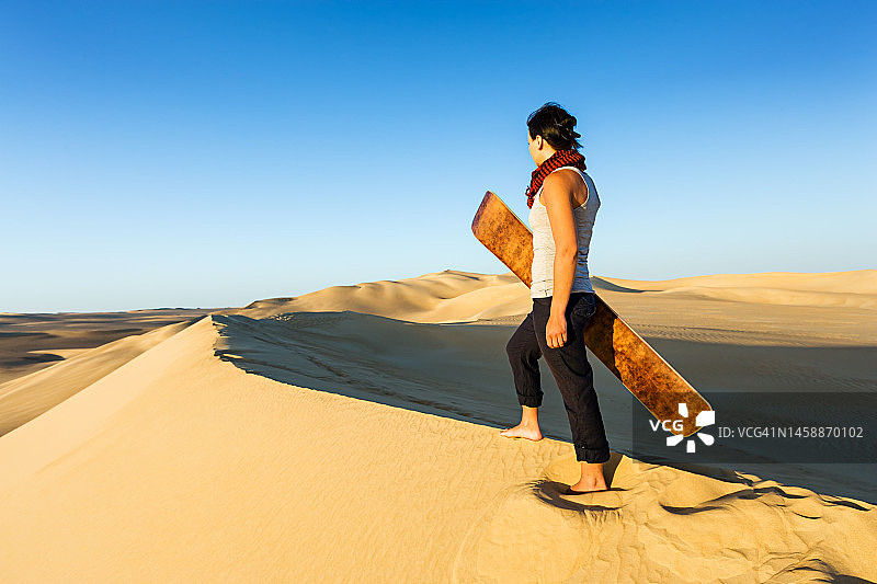 年轻女子在非洲撒哈拉沙漠滑沙图片素材