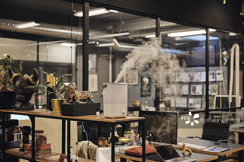 架子上释放雾气的加湿器，位于现代办公室图片素材