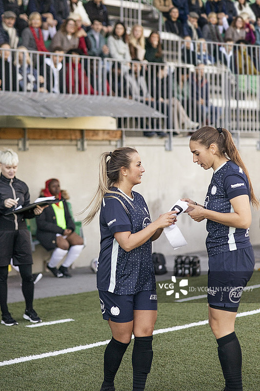 比赛中，女足队员在场上讨论，手持队长袖标图片素材