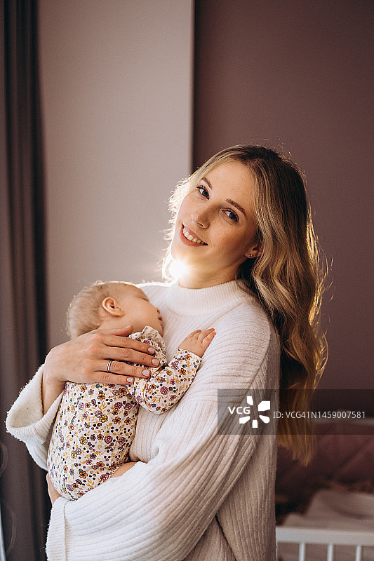 可爱的小女婴在年轻美丽的母亲怀里睡觉图片素材