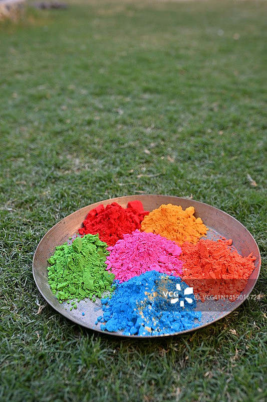 草地上放着一盘胡里节彩色粉末图片素材