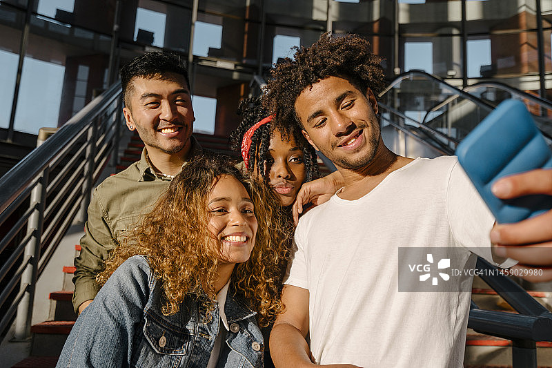 在车站，微笑的多民族朋友用智能手机自拍图片素材