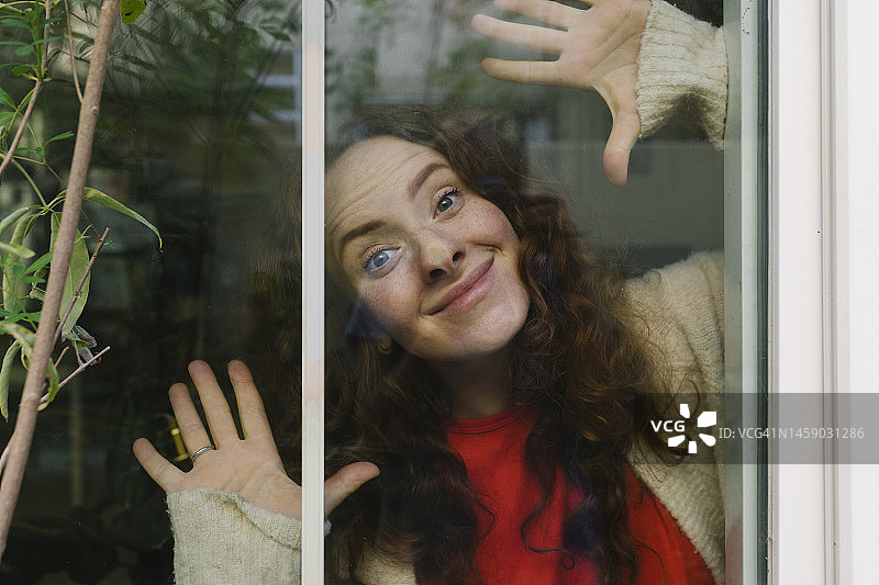 微笑的女人透过玻璃做鬼脸图片素材