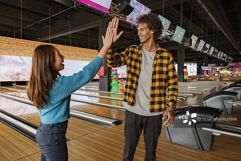 年轻女子在保龄球馆与朋友击掌图片素材