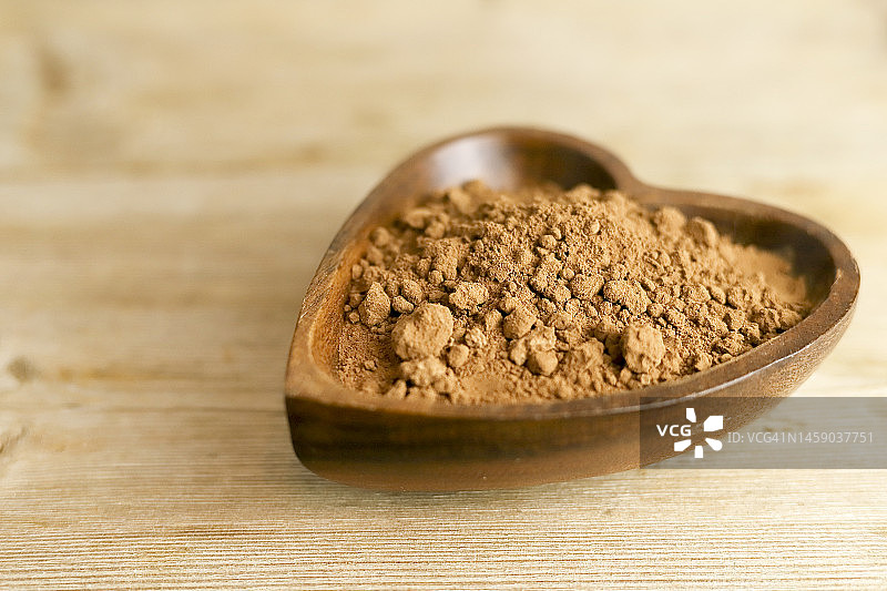 竹制心形碗中堆放的黑可可粉特写图片素材