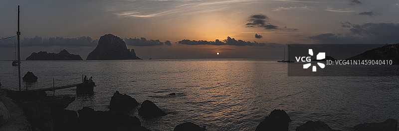 西班牙巴利阿里群岛日落时分的海滨，背景是埃斯维德拉岛的轮廓图片素材