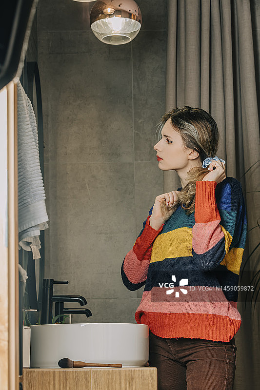 女孩在家中站在浴室镜子前扎头发图片素材