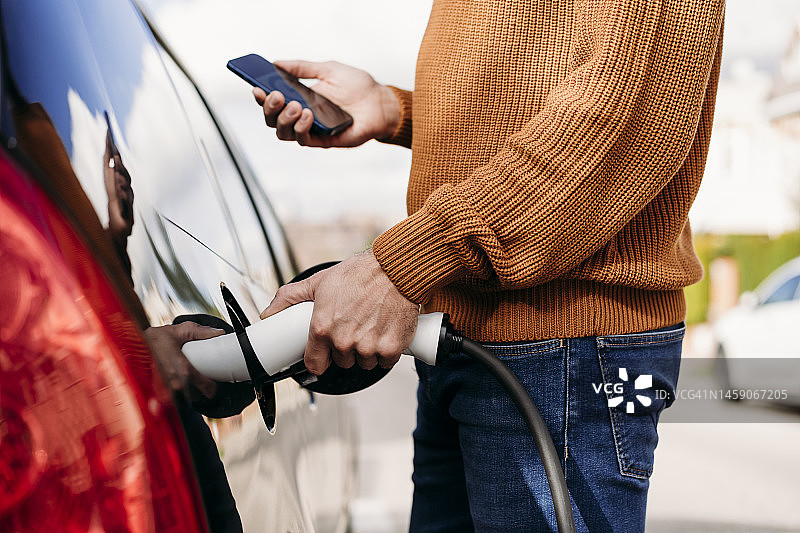 男子在充电站用智能手机连接电源插头图片素材