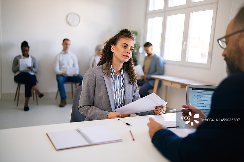 在与招聘人员进行面试时，手持申请表的女性候选人图片素材