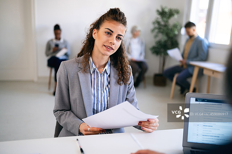 在与招聘人员进行面试时，手持申请表的女性候选人图片素材