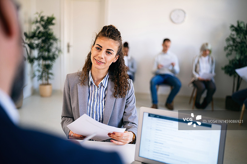 在与招聘人员进行面试时，拿着简历的女候选人图片素材