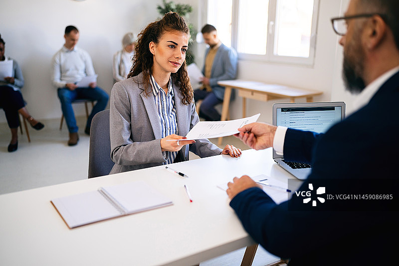 白人女性候选人在面试中向招聘人员递交简历图片素材