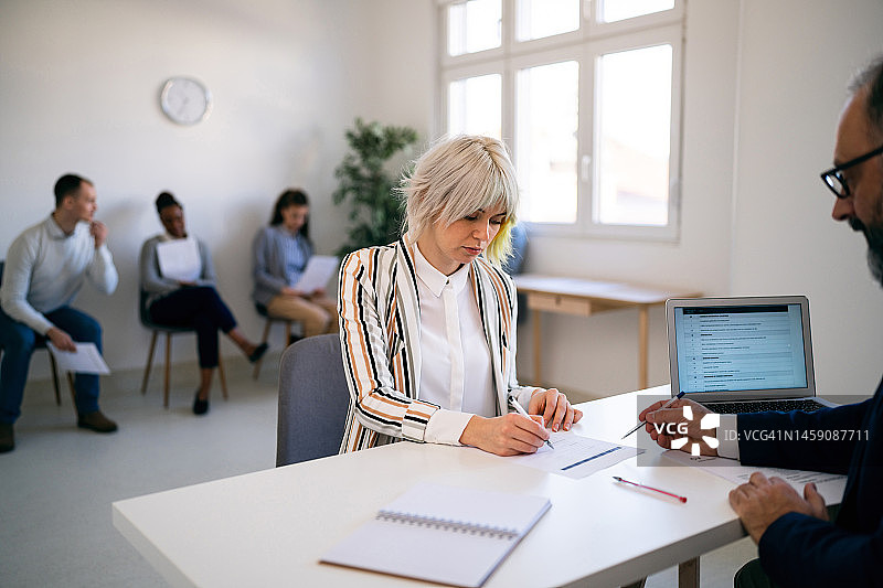 女应聘者在与招聘人员进行面试时填写申请表图片素材