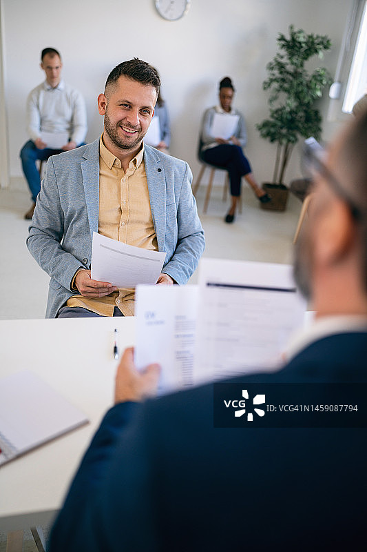 男候选人拿着简历与招聘人员进行面试图片素材