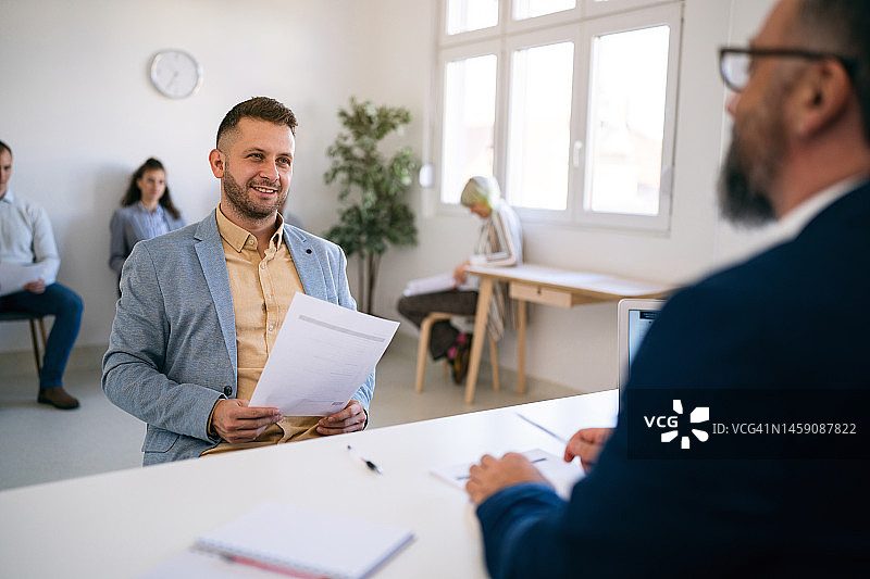 男候选人拿着简历与招聘人员进行面试图片素材