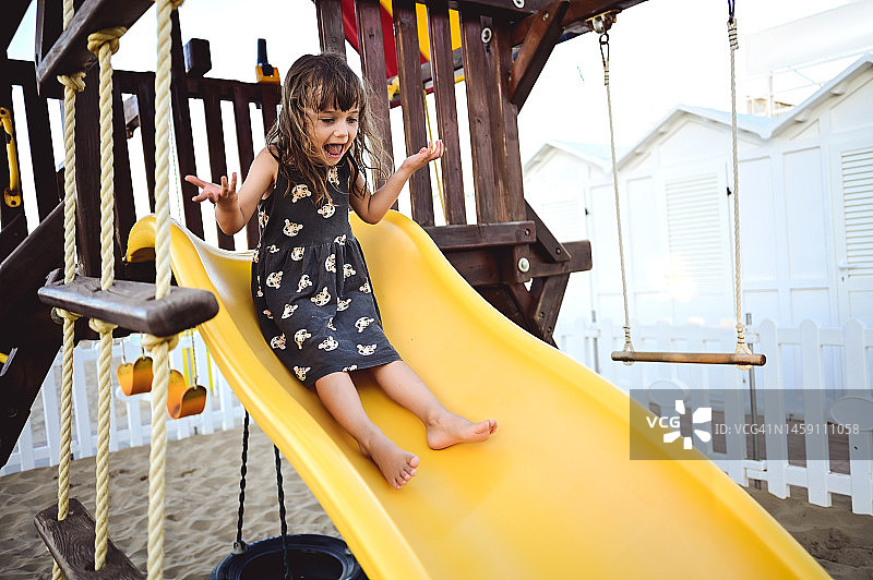 在黄色操场滑梯上快乐的小女孩图片素材