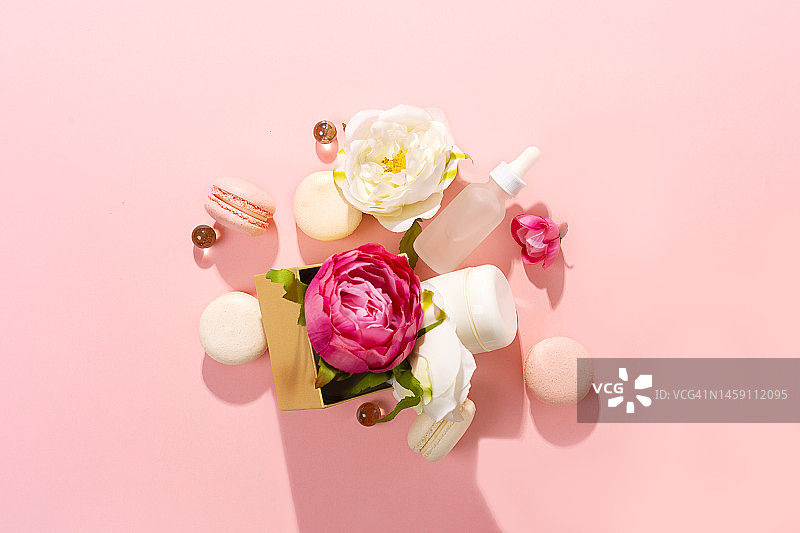 时尚美容产品概念，化妆品瓶中的面部精华液、护手霜以及粉红色和白色牡丹花图片素材