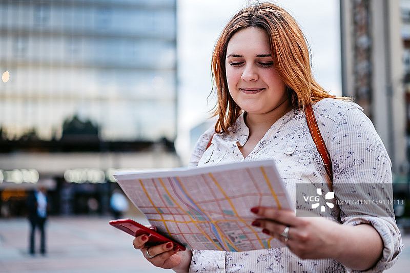 在城市里看地图的年轻女游客图片素材