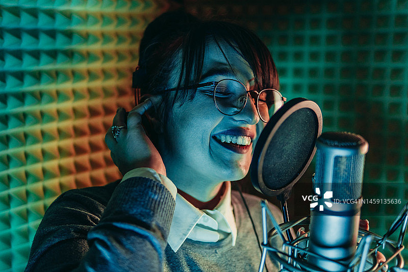 年轻女子在录音棚里用麦克风唱歌图片素材