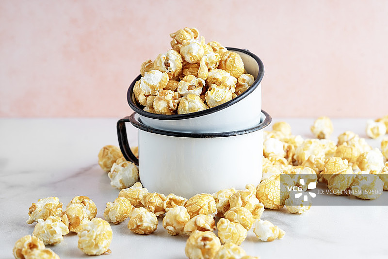 粉色背景上的碗装焦糖爆米花图片素材