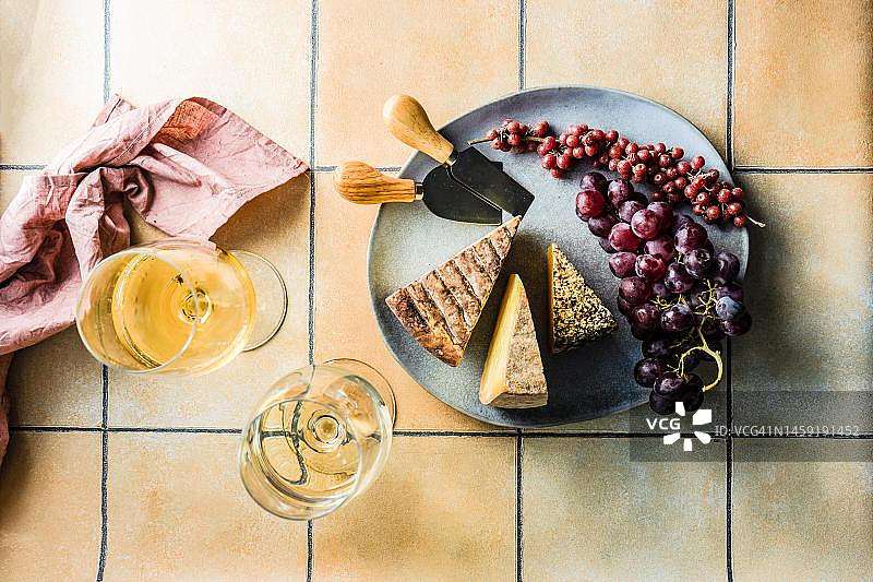 奶酪、伏牛花和葡萄拼盘与两杯白葡萄酒俯视图图片素材