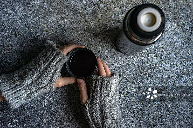 戴着露指手套的人拿着热饮的俯视图图片素材