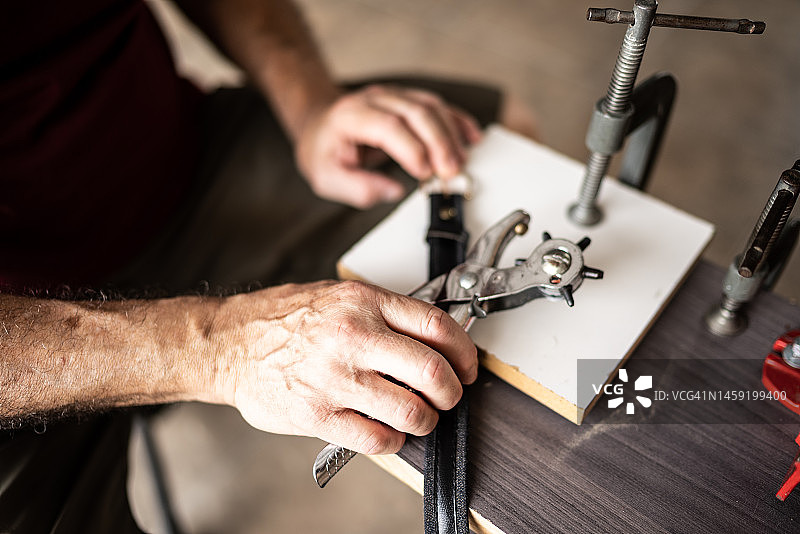 老年男人在家使用皮革锥子特写图片素材