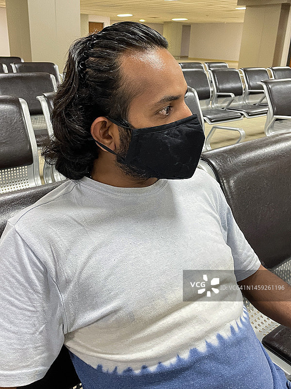 印度亚洲男子戴口罩坐在空荡荡的机场候机室特写，预防新冠病毒图片素材