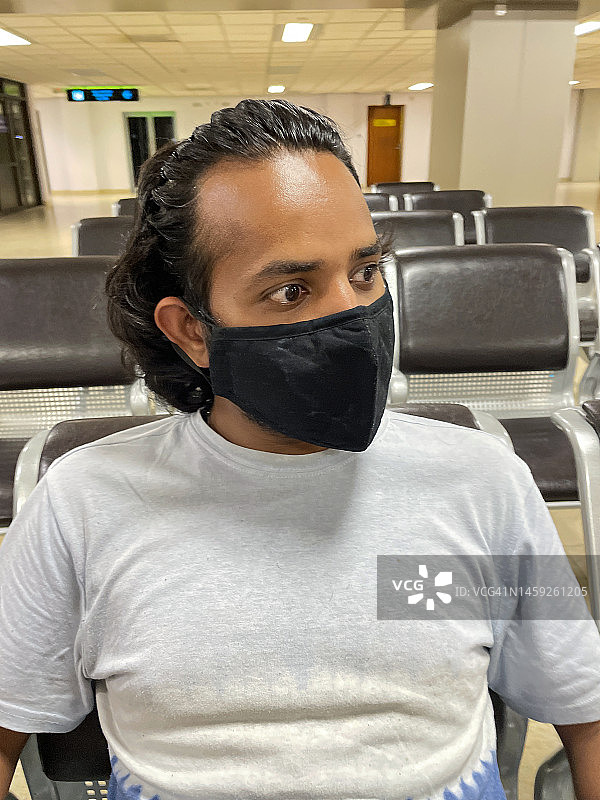 印度亚洲男子戴口罩坐在空荡荡的机场候机室特写，预防新冠病毒图片素材