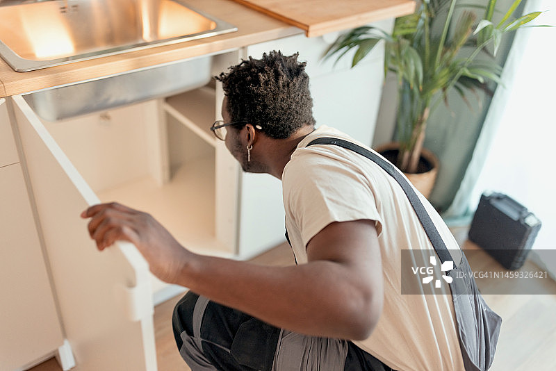 在水槽下维修管道的水管工图片素材