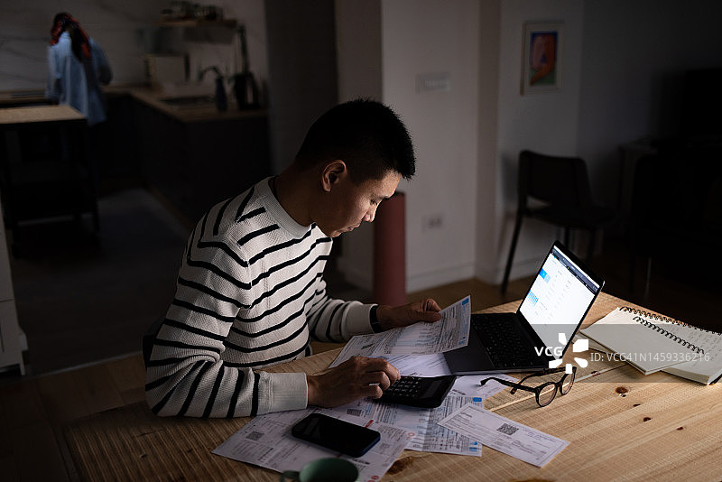 亚洲男人在家计算他的财务账单图片素材