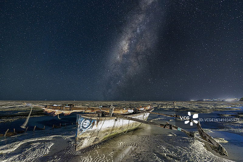 空旷海滩上单桅三角帆船上空的银河图片素材