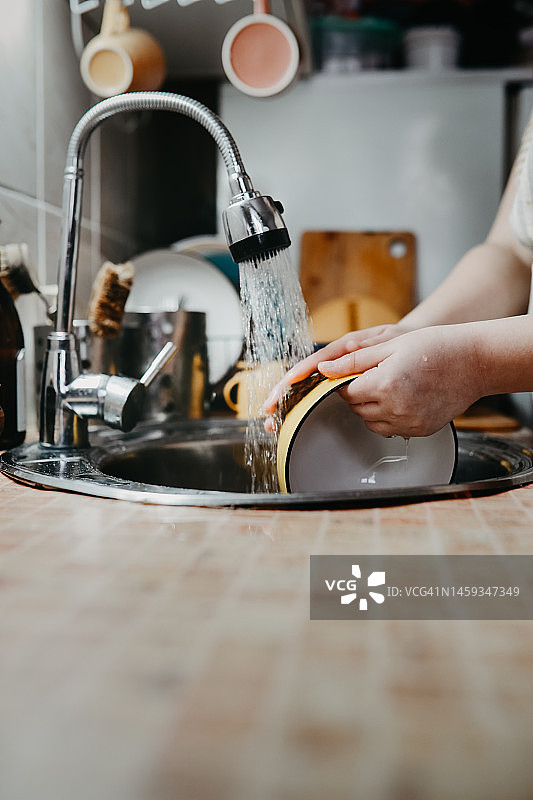 在家中水槽里用黄麻环保洗碗布洗碗。厨房的房屋里有复制空间和垂直空间。图片素材